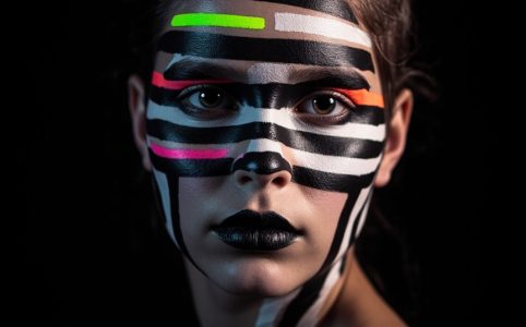 Портрет с геометрическим чёрно-белым и неоновым макияжем, ломающим распознавание лиц
